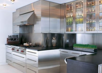 Taking inspiration from professional catering kitchens, this design was completed with a Wolf cooking appliance, extraction and bespoke glazed steel wall units.